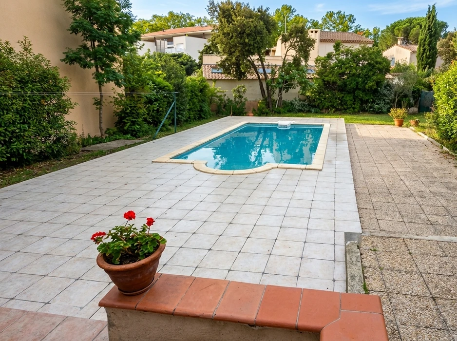 Piscine rectangulaire extérieure à débordement partiel, entourée d'une terrasse en dalles de béton blanc jointé
