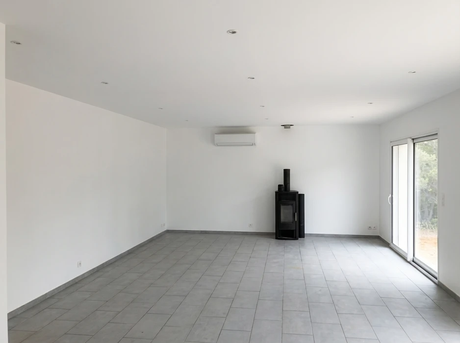 Pièce vide, lumineux séjour contemporain avec sol en carrelage gris clair, murs blancs et plafond à spots encastrés