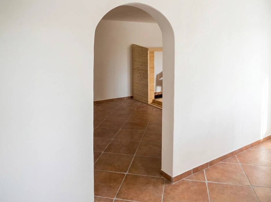 Intérieur vide avec arche en plâtre blanc donnant sur une pièce adjacente