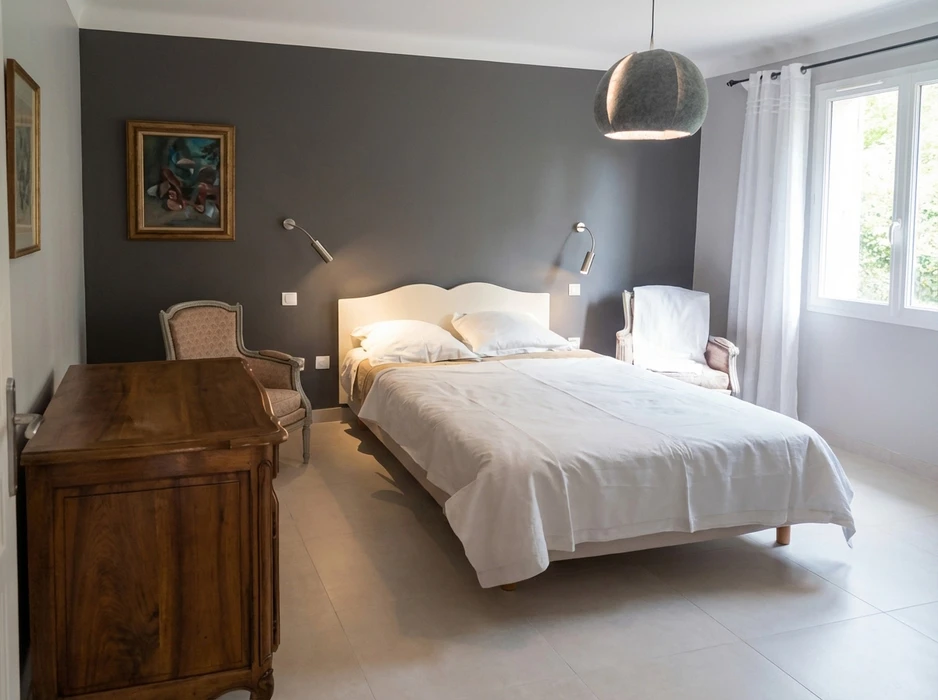 Un artisan en tenue de travail beige installe un parquet stratifié dans une pièce blanche avec radiateur et fenêtre